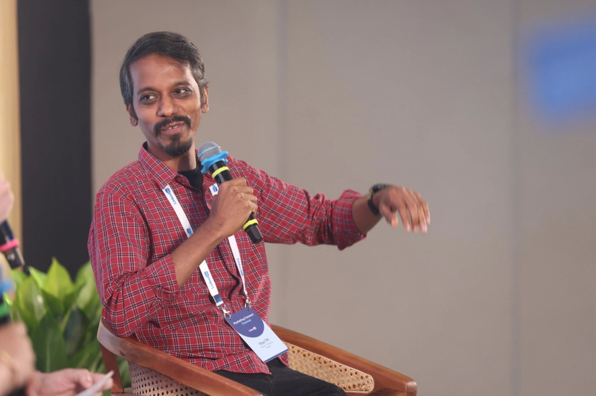 Raja speaking in a red checked shirt